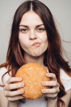 woman with a hamburger in her hands a snack fast food close-up. High quality photo