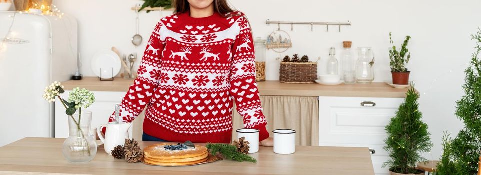 Merry Christmas and Happy New Year. Happy young brunette woman in christmas sweater making hot drinks in the kitchen