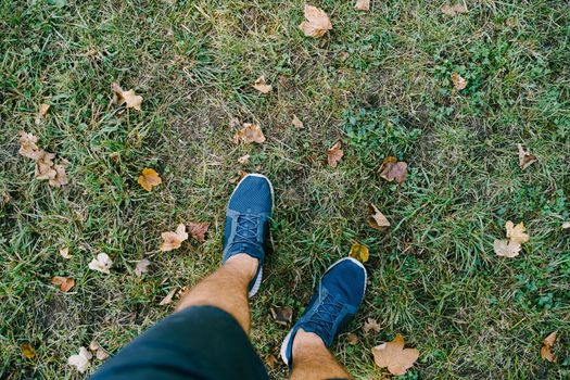 Male legs in sneakers and shorts on the grass. Close-up. High quality photo