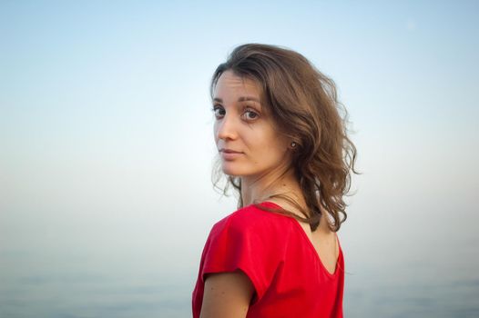 Young girl in red dress on the sea and blue background, summertime, travelling concepts.