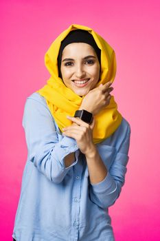 cheerful woman in yellow hijab electronic watch technology user pink background. High quality photo