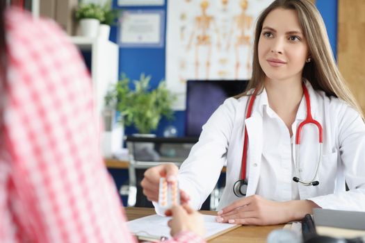 Portrait of qualified female doctor give tablets to patient for faster recovery. Woman on appointment get advice from professional. Medicine, help concept