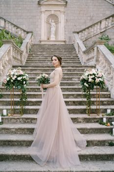 Bride with a bouquet on the stone steps of an ancient villa. High quality photo