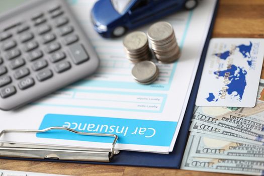 Close-up of car insurance paper calculator stack of coins and banknote on desk. Sign contract and protect your car from accident. Vehicle insurance concept