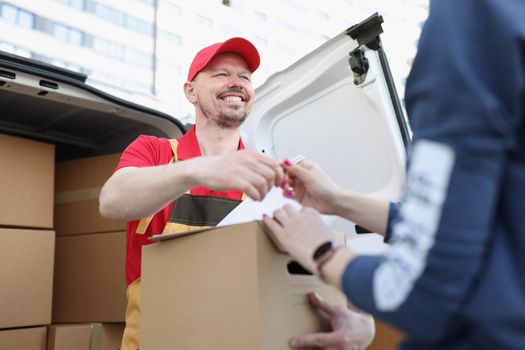 Portrait of courier and receiver make trade with signature on document for order. Worker delivered box fast on personal address. Delivery service concept