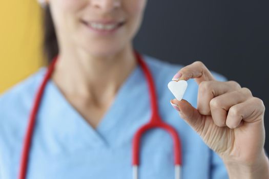 Close-up of female medical worker show small white heart on camera. Save life through donation or charity. Medicine, cardiology, healthcare, help concept
