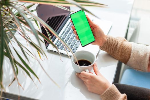 Young woman working,scrolling and checking her phone. Focus on the mobile phonechromakey, green screen on screen.