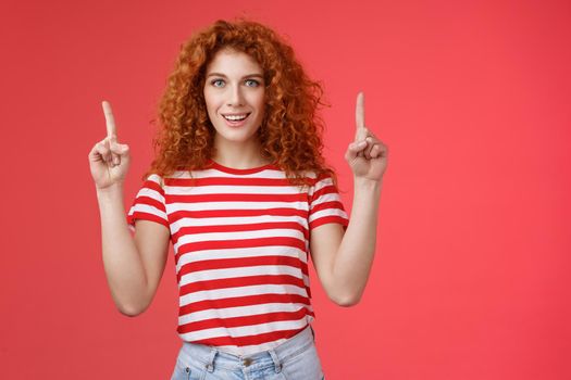 Excited good-looking cheeky redhead ginger girl curly natural hair pointing raised index fingers up smiling impressed thrilled advising store directing promo advertising awesome haircare product.