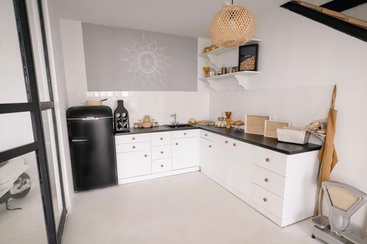 Light Vintage Style Kitchen with Black Small Fridge, Black Marble Countertop, Spice Shelves, Large White Mandola on a Gray Background on the Wall. High quality photo