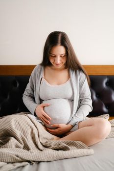 Pregnant woman hugs her belly with her hands and looks at it. High quality photo