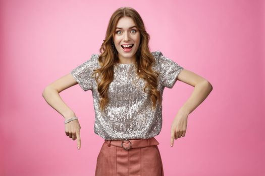 Studio shot impressed excited attractive young fashionable woman drop jaw thrilled pointing down index fingers amazing awesome promo advertisement, showing copy space astonished overwhelmed.