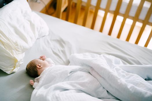 Baby sleeps in bed covered with a blanket. High quality photo