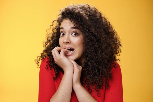 Portrait of worried woman biting fingernails as feeling insecure and scared of boyfriend find out she spent all money on credit card standing silly acting like unaware looking nervously at camera.