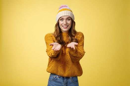 Girl suggesting take her heart smiling broadly friendly extending arms towards camera proposing help smiling delighted feeling upbeat wanna thank friend grateful appreciating effort, yellow wall.