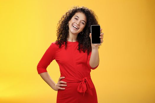 Carefree satisfied and happy attractive businesswoman presenting her best friend new mobile phone showing smartphone at camera laughing and smiling joyfully delighted with new purchase. Emotions and technology concept