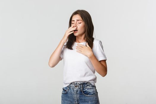 Young woman with allergy sneezing. Girl feeling sick having runny nose.