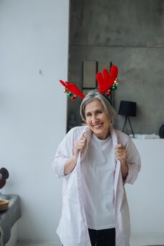 Grandma wearing deer christmas hat, happy smiling face looking at the camera. positive person.