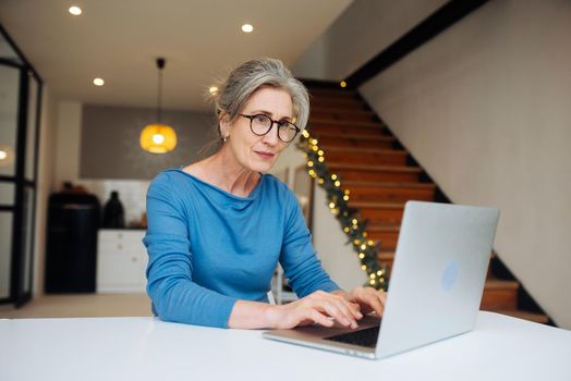 Happy mature middle aged elderly woman reading good news looking at laptop