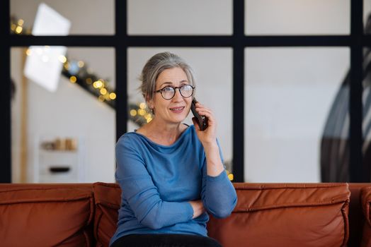 Image of senior woman talking on smartphone at home