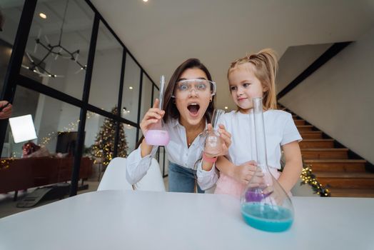 Young woman and little girl mix flasks indoors, close view.