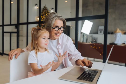 Child and granny looking at the camera with laptop at home