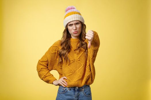 Lame dislike unfollow. Portrait disappointed displeased picky young judgemental woman show thumb-down cringing grimacing unsatisfied expressing disapproval antipathy, yellow background.