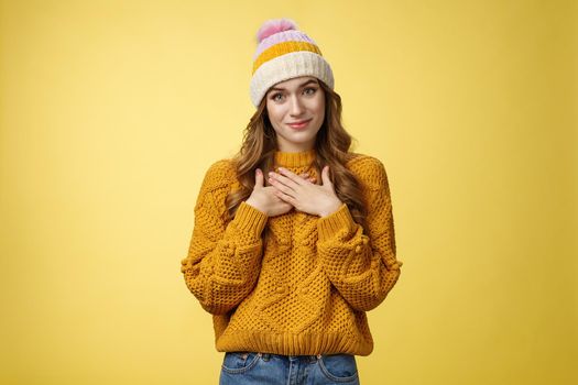 Thankful touched young woman receive warm pleasant compliment press palms chest thanking appreciating nice moving gesture smiling delighted happy grateful standing yellow background. Copy space