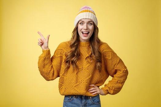 Amazed surprised carefree happy young joyful woman laughing surprised widen eyes wondered see funny prank pointing upper left corner excited discussing friends new shopping centre, yellow background.