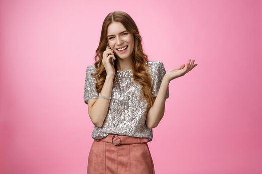 Sociable friendly-looking smiling happy glamour rich girl talking smartphone calling friend pleasant funny conversation laughing out loud joking gesturing talk mobile phone, pink background.