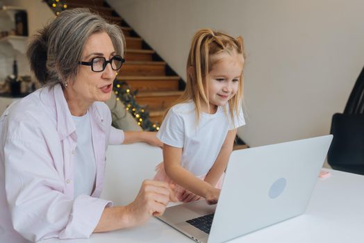 Child and granny looking at the camera with laptop at home