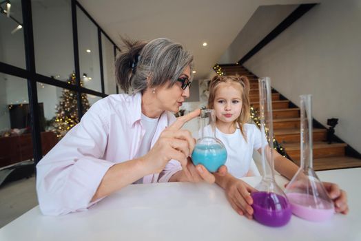 Engaging science. Attentive old grandma assist grandkid in funny scientific research