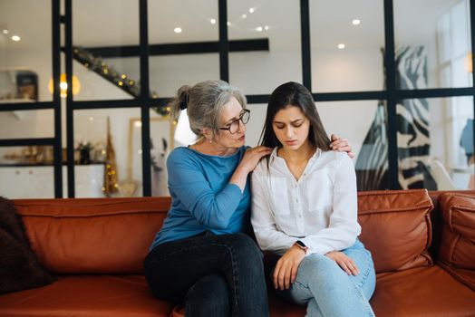 Grandmother comforting her sad granddaughter at home. Support concept