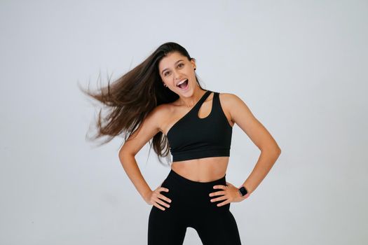 Sporty fit beautiful young woman in sportswear bra and black pants, isolated, white background