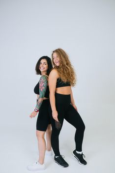 Two young women posing over white background. Two girlfriends, body positive concept