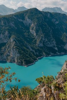 The concept of eco-tourism and active recreation. National Park. Mountain Emerald lake in the wooded mountains. Sunny day in autumn.