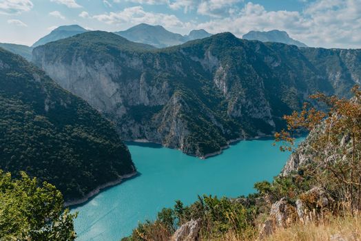 The concept of eco-tourism and active recreation. National Park. Mountain Emerald lake in the wooded mountains. Sunny day in autumn.