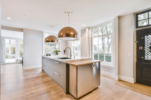 Open plan kitchen with dark wood cabinets and pendant lamps in luxurious apartment