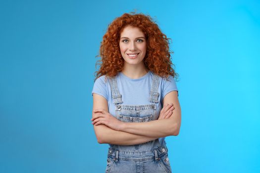 Motivated empowered sassy redhead female believe girl power cross arms chest self-assured confidently know how deal any problem smiling cheeky determined stand denim overalls blue background.