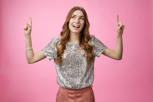 Charming excited good-looking glamour young girl look up thrilled joyful pointing index finger top upwards smiling amazed enjoyment perfect weather, standing happily pink background.