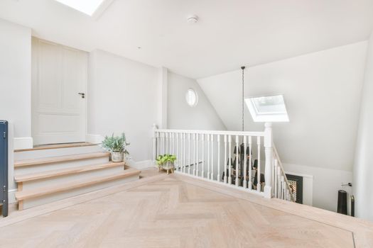 Top landing of stairs with wood floor and white walls