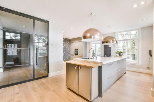 Open plan kitchen with dark wood cabinets and pendant lamps in luxurious apartment