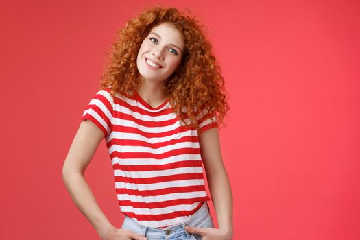 Cheerful european redhead fashionable happy redhead curly-haired girl tilt head excited hold hands jeans pockets smiling broadly toothy glad grin enjoy summer vibes romantic girlfriend date.