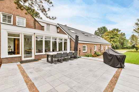 The facade of a one-story brick house with a green fresh lawn in front of the house