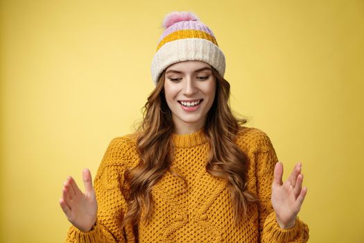 Attractive tender girl retelling friends what got b-day present describing large present box smiling happily look down shaping big thing talking joyfully excited, standing happy yellow background.