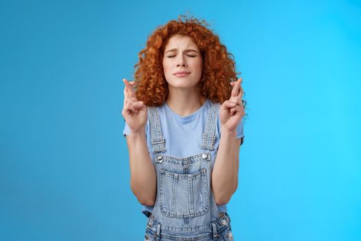 Intense nervous attractive redhead curly-haired hopeful focused girl praying supplicating asking god make dream come true cross fingers good luck anticipating important news wanna wish fulfill.