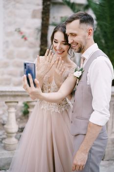 Bride and groom take a selfie with rings on their fingers on a smartphone. High quality photo