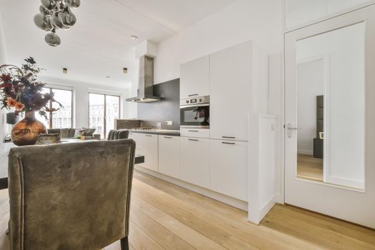 Interior of contemporary kitchen with stylish black cupboards and appliances near dining area in contemporary apartment