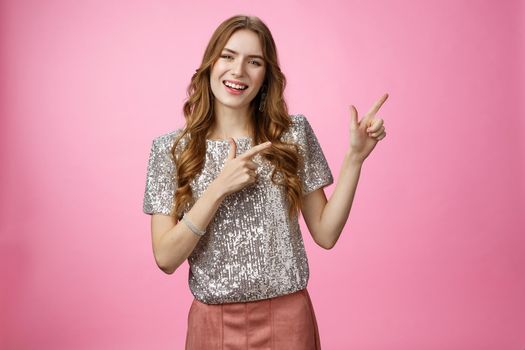 Positive friendly-looking glamour stylish young woman inviting girlfriend check out new appartment throw party smiling broadly pointing upper right corner grinning happily enjoying awesome evening.