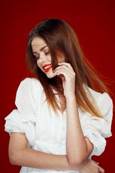 cheerful red-haired woman with red lips white dress red background. High quality photo