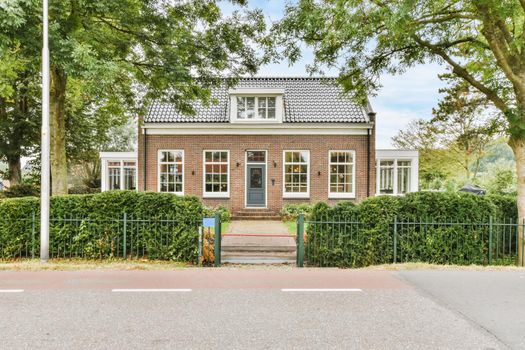 View of an on-storey brick house with greenery on the street